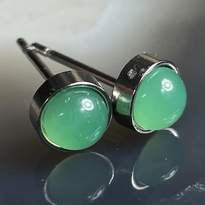 Puede incluir: Un par de pendientes de plata con piedras redondas verdes.