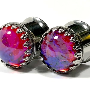 May include: Pair of silver ear gauges with a red and purple iridescent glass inlay and a decorative silver border.