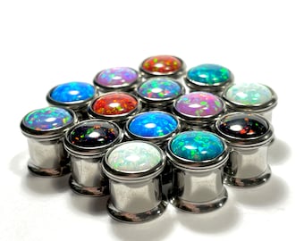 May include: A collection of 15 stainless steel ear gauges with opal stone inserts in various colours, including blue, green, red, white, and black.
