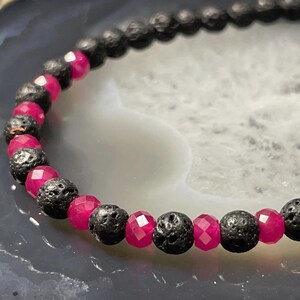 Puede incluir: Una pulsera de cuentas con cuentas alternas de roca volcánica negra y cuentas de piedras preciosas rosas brillantes y facetadas. Un accesorio sencillo pero llamativo.
