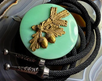 Corbata bolo de vidrio de uranio jadeíta y roble, reactiva a los rayos UV.