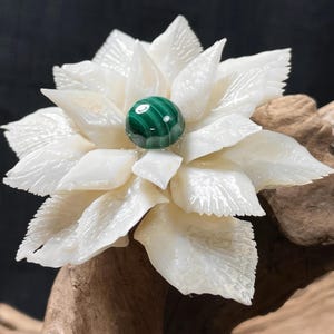 May include: A white shell flower brooch with a green malachite stone in the center.