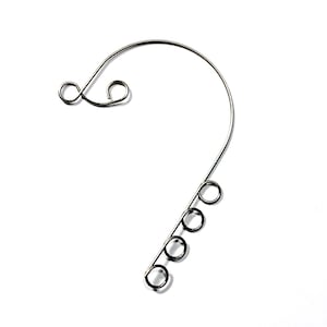 May include: A silver-colored metal earring component with a curved design. The top features two small, looped swirls, and the bottom has five evenly spaced circular loops. The earring component is set against a white background.
