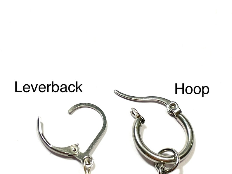 May include: Close-up of two different earring styles: a leverback and a hoop. The leverback earring has a curved, hinged design. The hoop earring is a small, circular design. Both earrings are made of a shiny, silver-colored metal.
