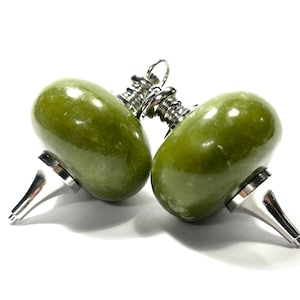 May include: Two green stone pendant charms with silver metal tops and loops. The charms are shaped like a rounded teardrop with a pointed bottom.