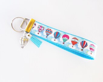 Keychain with the word serene stamped on a washer with hot air balloon charm and green crystal.
