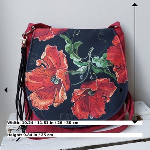 May include: A red suede crossbody bag with a black fabric flap featuring a floral design of red poppies on a black background. The bag measures 10.24 to 11.81 inches wide and 9.84 inches high.