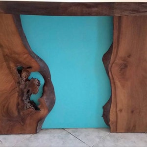 May include: A wooden table with a turquoise blue resin inlay. The table has a live edge design and a natural wood finish.