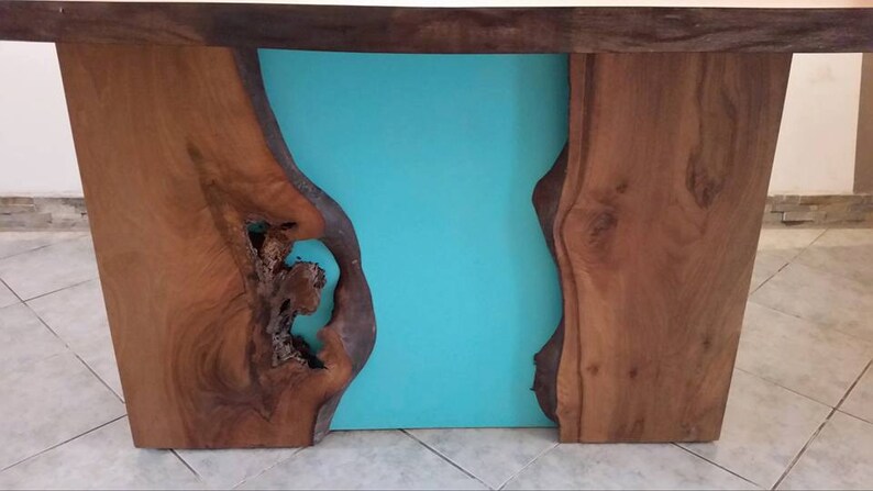 May include: A wooden table with a turquoise blue resin inlay. The table has a live edge design and a natural wood finish.