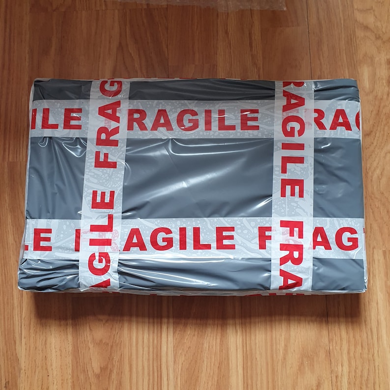 May include: A gray package wrapped in white tape with the words "Agile Fragile" printed in red.