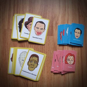 May include: A collection of horror movie character cards, including Freddy Krueger, Hannibal Lecter, and Frankenstein's Monster. The cards are yellow-bordered with character illustrations and names. Additional cards are blue and pink.