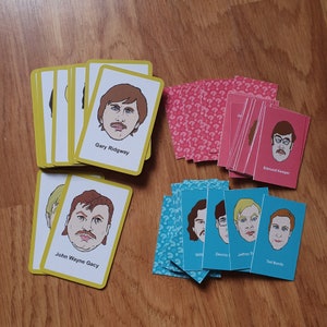 May include: A set of yellow and blue playing cards with illustrations of men's faces and names. The cards are arranged in two rows, with the yellow cards on top and the blue cards on the bottom. The names on the cards include Gary Ridgway, John Wayne Gacy, Will, Dennis, Jeffrey D., and Ted Bundy.