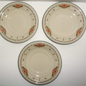 May include: Three white ceramic saucers with a green rim and a colorful geometric pattern. The pattern features red, yellow, and green colors.
