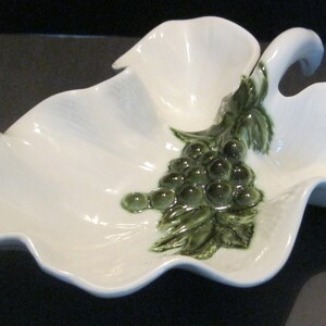 May include: White ceramic serving dish shaped like a leaf with a green grape design. The dish has three sections and a handle.