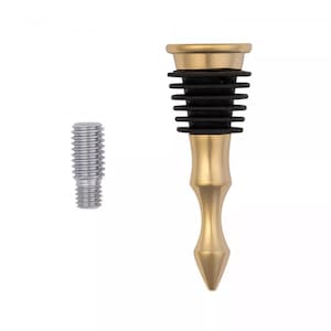 May include: A gold-toned metal bottle stopper featuring a tiered black rubber seal and a pointed base, accompanied by a separate silver-toned threaded metal screw component. The stopper has a smooth, polished finish and a tapered, elongated shape.