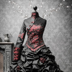 May include: A black and red gothic-style dress with a fitted bodice and a full skirt. The bodice has a lace overlay and a high collar. The skirt is made of layers of tulle and has a ruffled hem.
