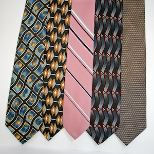 May include: Five neckties displayed side-by-side. The first features a blue grid with orange circles. The second has a black background with tan and white diamonds. The third is solid pink with diagonal white and black stripes. The fourth has wavy gray and maroon lines. The fifth is a tan and blue geometric pattern.