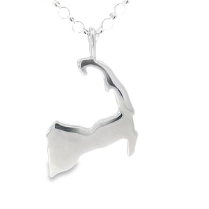 May include: A silver pendant necklace featuring the outline of Cape Cod, Massachusetts. The pendant is a polished, shiny silver and hangs from a delicate chain. The necklace is a simple, elegant piece of jewelry.