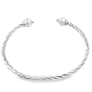 May include: A silver-colored cuff bracelet with a twisted rope design. The bracelet has a smooth, polished finish and features a small, round bead at each open end. This piece of jewelry is a classic and versatile accessory.