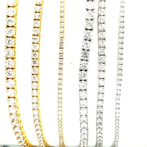 May include: Five diamond tennis bracelets, two in yellow gold and three in white gold. The bracelets are all the same style, with small round diamonds set in a continuous line.