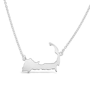May include: A silver necklace featuring a pendant shaped like the outline of Cape Cod. The chain is a delicate, silver curb chain.