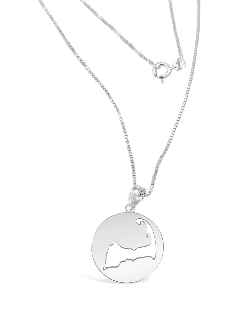 Puede incluir: Un collar de plata con un colgante circular que presenta un dise&ntilde;o recortado en forma de Cabo Cod.