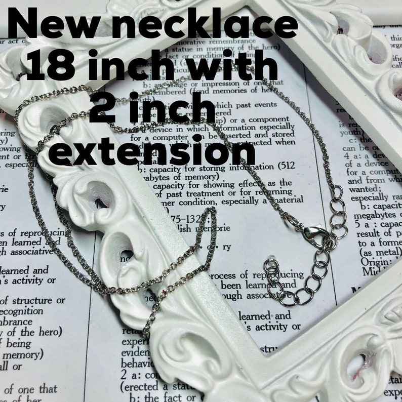 May include: A silver chain necklace with a 2 inch extension. The necklace is 18 inches long. The necklace is laying on a white surface with text in the background.