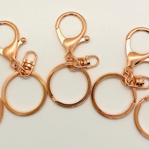 Peut inclure: Cinq porte-clés en or rose avec un fermoir pivotant et un anneau rond.