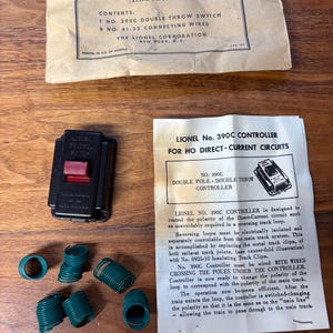 May include: Vintage Lionel train set components, including a black and red controller, green connecting wires, and instruction sheets. The catalog reads "Catalog No. 390C". The instruction sheet reads "Lionel No. 390C Controller".