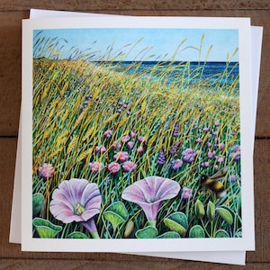 May include: A watercolor painting of a field of wildflowers and tall grass with a blue ocean in the background. Two pink flowers are in the foreground, and a bumblebee is flying near the flowers.