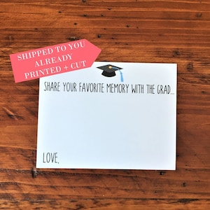 May include: A white card with the text "SHARE YOUR FAVORITE MEMORY WITH THE GRAD..." and "LOVE," printed on it. A red arrow with the text "SHIPPED TO YOU ALREADY PRINTED + CUT" is attached to the top of the card. A blue graduation cap with a blue tassel is on the card.