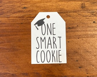 May include: White gift tag with a black graduation cap and the text "ONE SMART COOKIE".