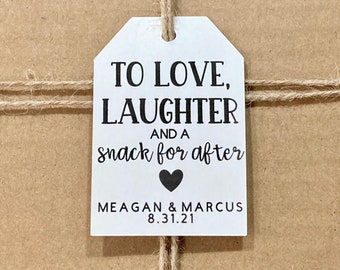 May include: White gift tag with black text that reads "To love, laughter and a snack for after" with a black heart symbol and the names "Meagan & Marcus" and the date "8.31.21".