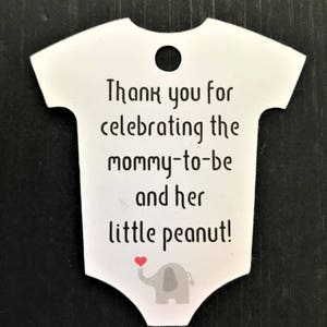 May include: White baby onesie shaped thank you tag with a gray elephant holding a red heart. The tag says "Thank you for celebrating the mommy-to-be and her little peanut!"