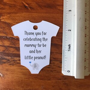 May include: White baby onesie shaped thank you tag with blue and gray elephant graphic and the text "Thank you for celebrating the mommy-to-be and her little peanut!"