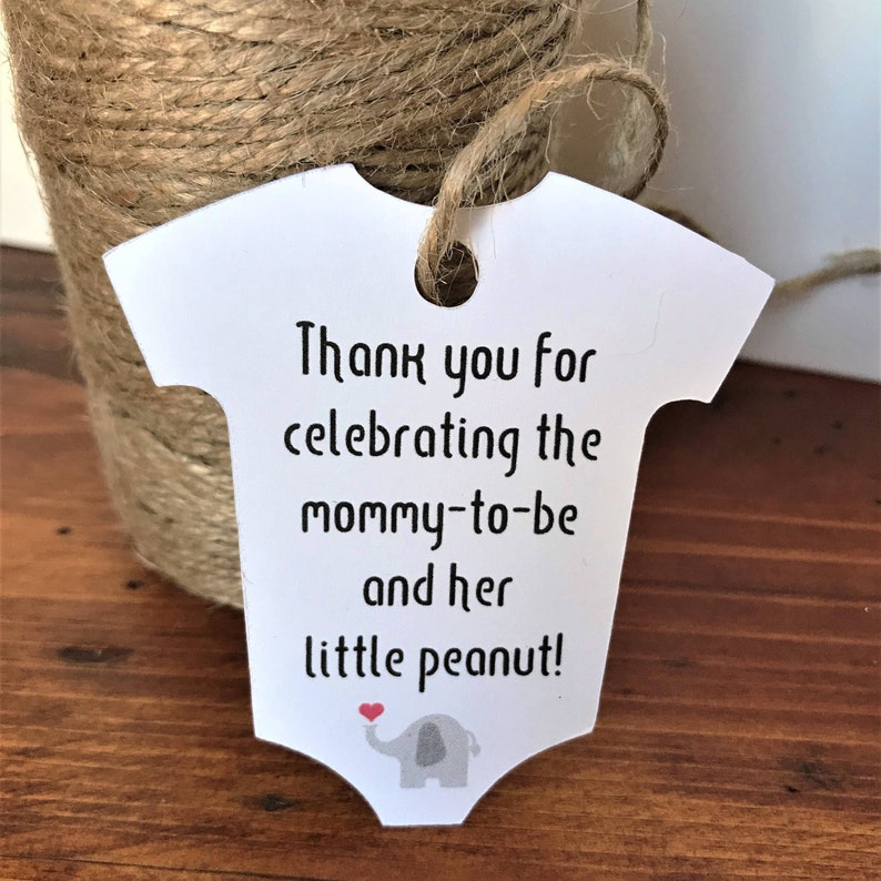 May include: White baby onesie shaped thank you tag with a gray elephant holding a red heart. The tag says "Thank you for celebrating the mommy-to-be and her little peanut!"