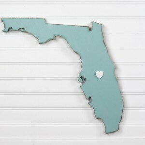 May include: A light blue wooden outline of the state of Florida with a white heart placed on the map.