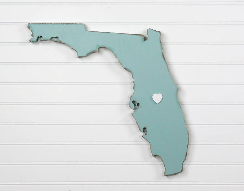 May include: A light blue wooden outline of the state of Florida with a white heart placed on the map.