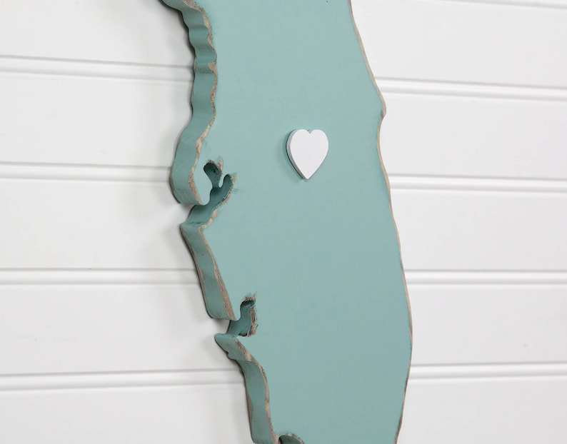 May include: A teal blue wooden outline of the state of Florida with a white heart in the center.