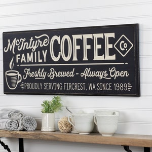 May include: Black and white sign with the text "McIntyre Family Coffee Co. Freshly Brewed - Always Open Proudly Serving Fircrest, WA Since 1989"
