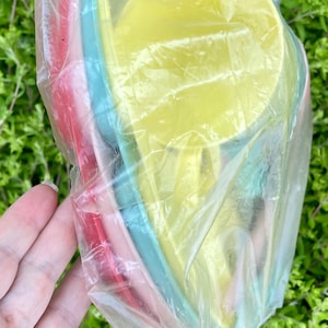 May include: A set of four nesting bowls in a clear plastic bag. The bowls are yellow, blue, pink, and red.