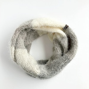 May include: A gray and white knit infinity scarf with a fuzzy texture.