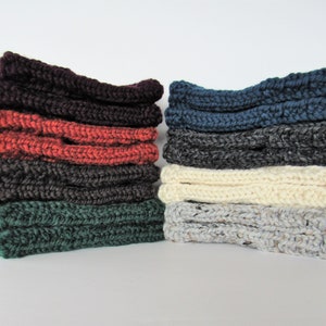 Puede incluir: Una pila de ocho diademas de punto en varios colores, incluyendo burdeos, naranja, gris oscuro, verde, azul marino, gris, crema y gris con motas blancas.
