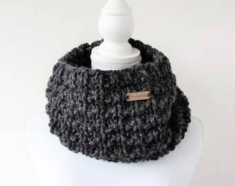 May include: A charcoal gray crocheted infinity scarf with a brown leather tag that reads "Handmade Gifts".