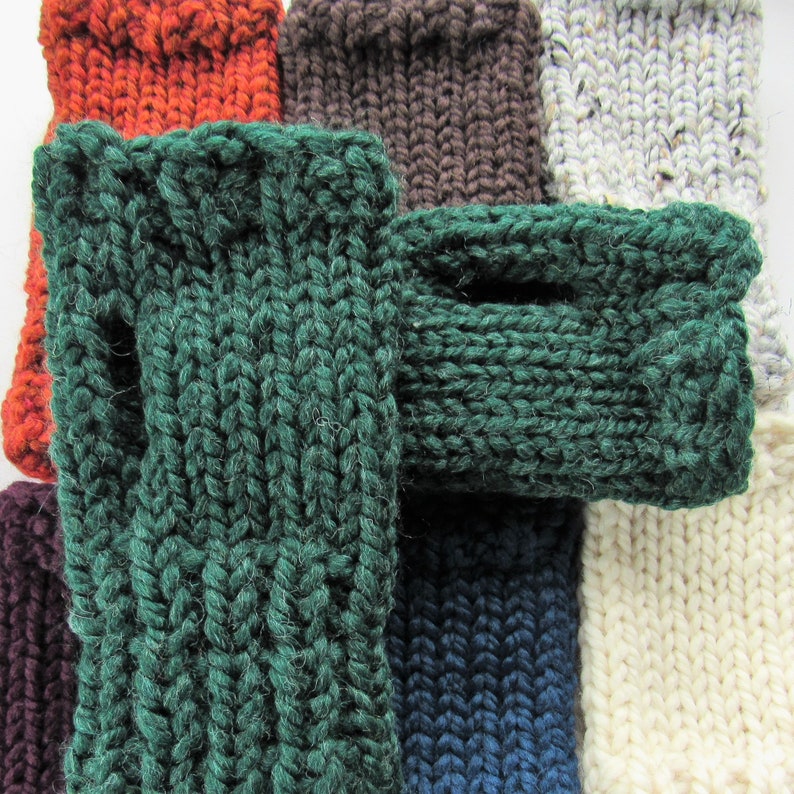 Puede incluir: Un conjunto de guantes sin dedos de punto en varios colores, incluyendo verde, marr&oacute;n, naranja, blanco y azul. Los guantes est&aacute;n hechos de un hilo grueso y texturizado y tienen un dise&ntilde;o simple y cl&aacute;sico.