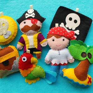 May include: A set of felt pirate-themed toys, including a pirate captain, a pirate, a treasure chest, a parrot, a skull and crossbones flag, and a palm tree.