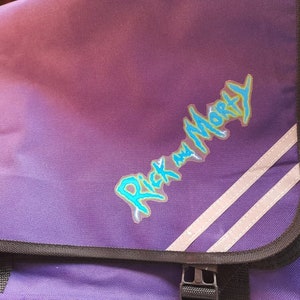 May include: Purple messenger bag with a reflective white stripe and the words "Rick and Morty" in blue and green lettering.