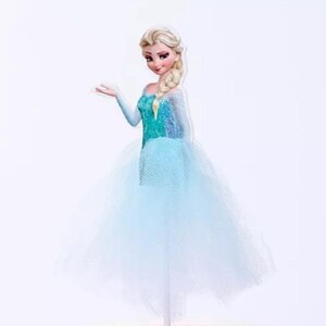 May include: A cutout of a cartoon character, a woman with blonde hair in a side braid, wearing a teal and blue dress with a tulle skirt. The character is posed with one arm outstretched.
