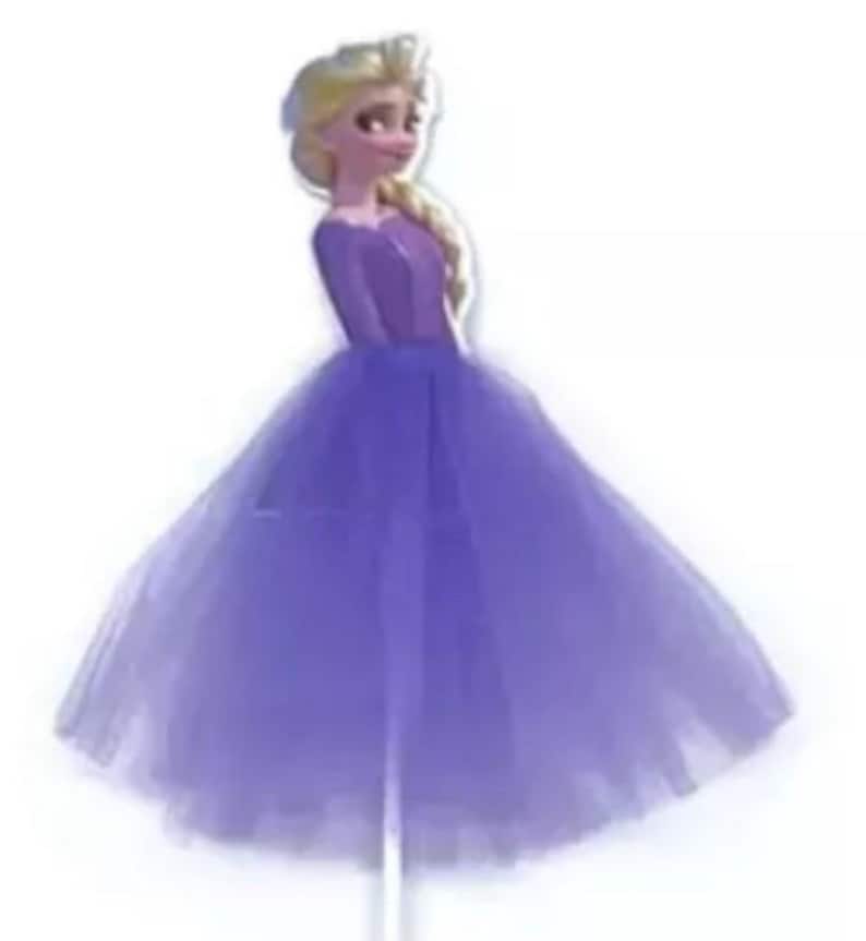 May include: A purple princess-themed cake topper featuring a cartoon character in a long, flowing purple dress. The character has blonde hair in a side braid and is smiling. The dress has a fitted bodice and a full, layered skirt.