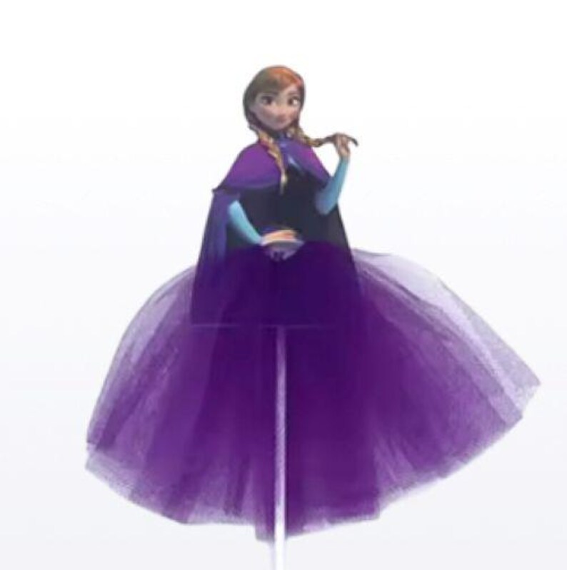 May include: A purple tulle skirt with a doll of a character from the animated movie Frozen. The doll has auburn hair in braids, a purple cape, and a blue and black dress. The skirt is attached to a clear stand.